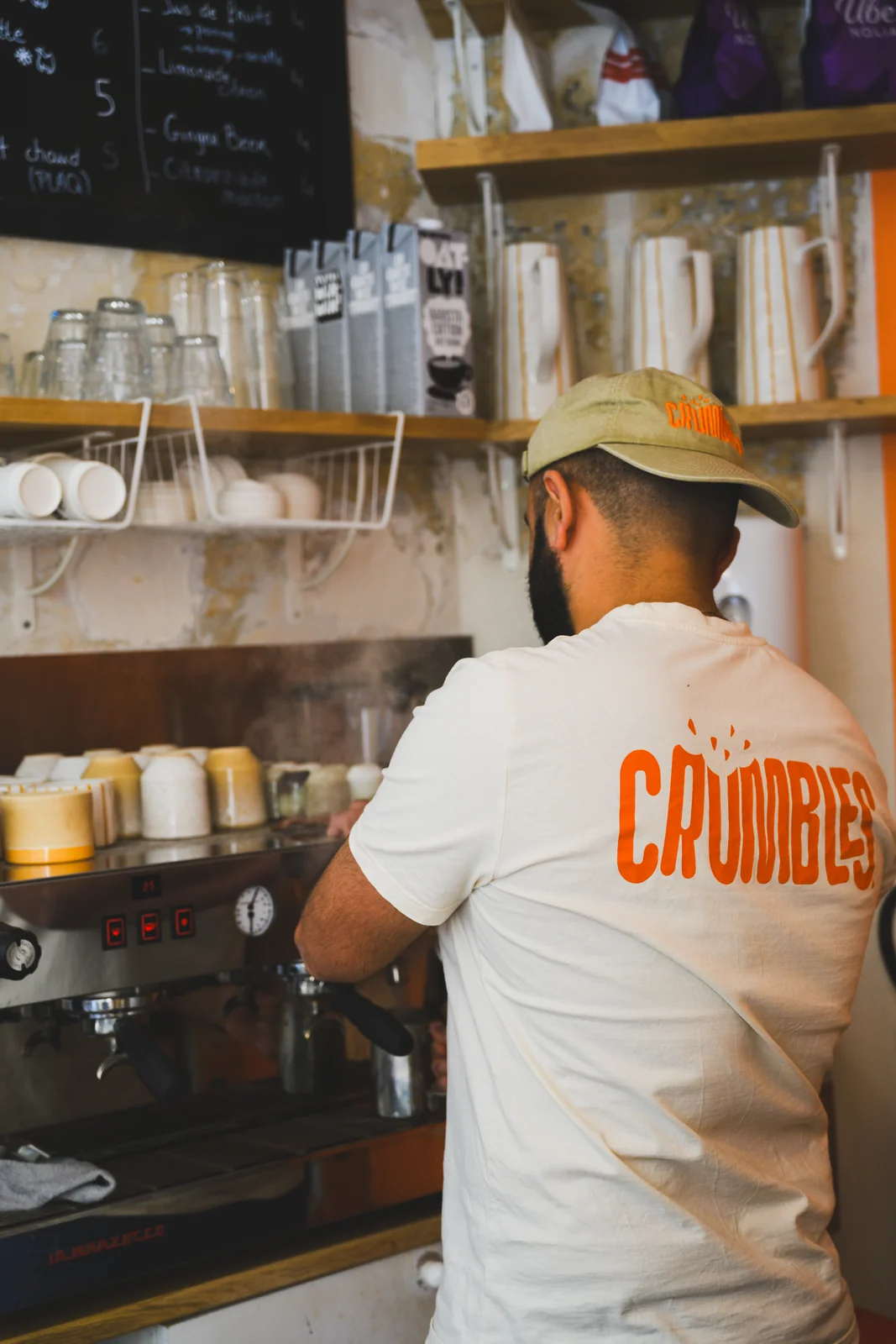 Arnaud Vely au comptoir, tire un espresso, t-shirt Crumbles vu de dos